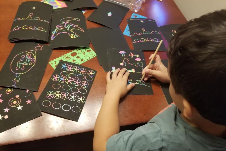 Child working on scratch art in a hotel room