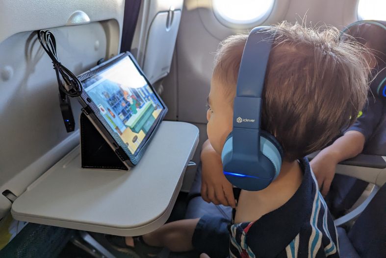 Child using headphones and tablet to watch a show on the plane